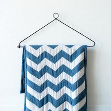 Load image into Gallery viewer, Chevron-patterned quilt hanging on a black metal display hanger against a white wall