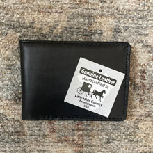 Load image into Gallery viewer, Black leather wallet with a 'Genuine Leather Handcrafted in Lancaster County, Pennsylvania, USA' label on a textured surface.