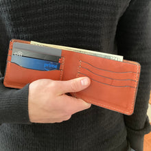 Load image into Gallery viewer, Person holding a brown leather wallet with cards and money