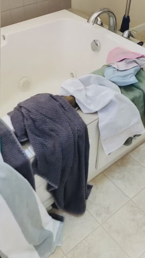 video showing lots of towels laying all over the side of a bath tub and then a wall mount laundry rack is placed on the wall next to the tub and shows all the towels hanging up neatly and organized