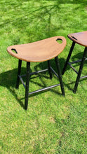 Load and play video in Gallery viewer, Video showing the 3 colors of saddle stools including special walnut stain, Michael's Cherry Stain and solid black.