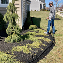 Load image into Gallery viewer, man walking with hose running along the bottom of hose guide stakes protecting the plants from the hose