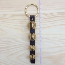 Load image into Gallery viewer, 4 sleigh bells on brass plated ring next to tape measure to show length
