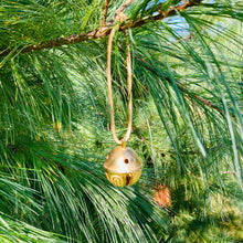 Load image into Gallery viewer, Santa bell on leather string hanging from a pine tree branch
