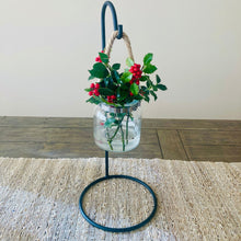 Load image into Gallery viewer, Decorative metal plant hook stand with a glass jar holding greenery and red berries on a wooden table.  Handmade Amish wrought iron decor for home and gift giving
