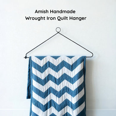 Blue and white chevron-patterned quilt on an Amish handmade wrought iron quilt hanger against a white background.