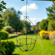Load image into Gallery viewer, Decorative metal hanging basket in a garden setting with greenery and flowers.
