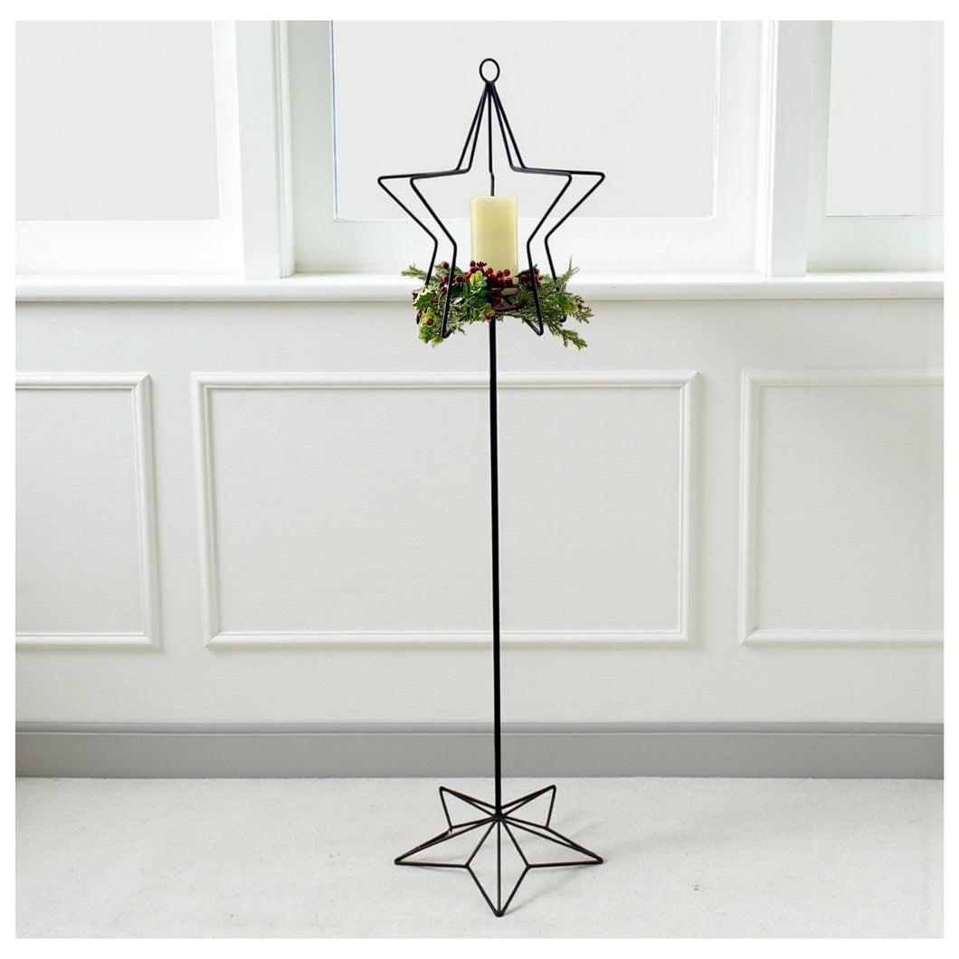 Wrought Iron Tall Candle Stand Christmas Home Decor.  Decorative black metal candle holder with star design against a white paneled wall.