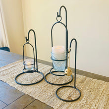 Load image into Gallery viewer, Farmhouse candle and ornament display stand for Christmas decor. Set of black metal candle holders on a wooden table with a woven table runner. 
