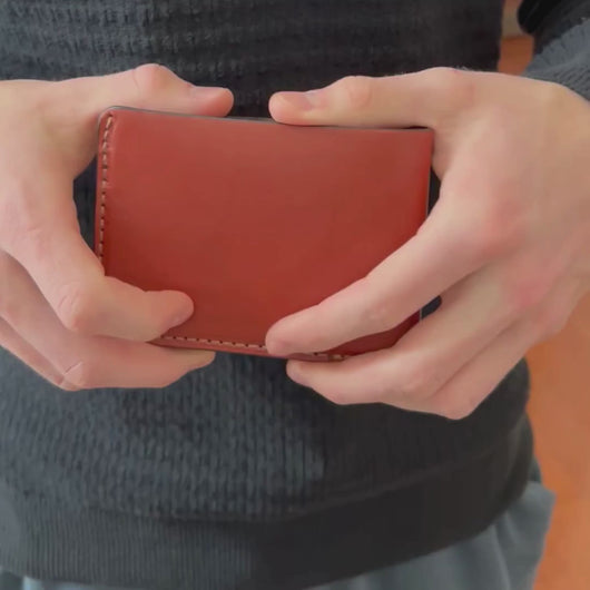 A man's hands showing three styles of wallets, two bifold wallets and one trifold wallet.  Wallets are Amish handmade in Lancaster County PA 