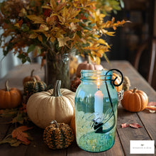 Load image into Gallery viewer, Decorative setting with pumpkins, a candle in a blue mason jar, and fall foliage on a wooden table.
