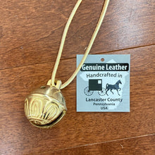 Load image into Gallery viewer, Solid brass bell on leather lacer next to the tag that reads Genuine Leather Handcrafted in Lancaster County Pennsylvania USA

