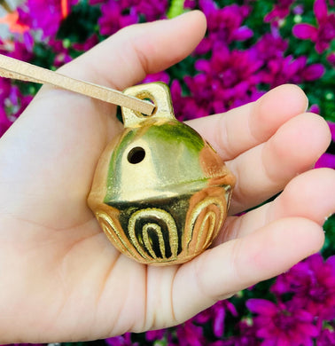 Solid Brass Bell with leather string in a child's hand